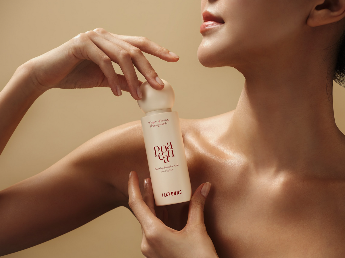 A woman holds a frosted bottle of Wash against a warm beige background.