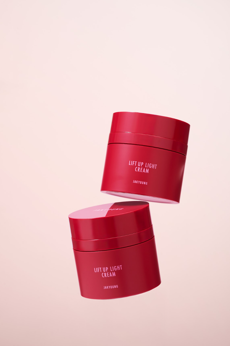 Two red cosmetic jars labeled 'LIFT UP LIGHT CREAM' floating against a soft pale pink background.